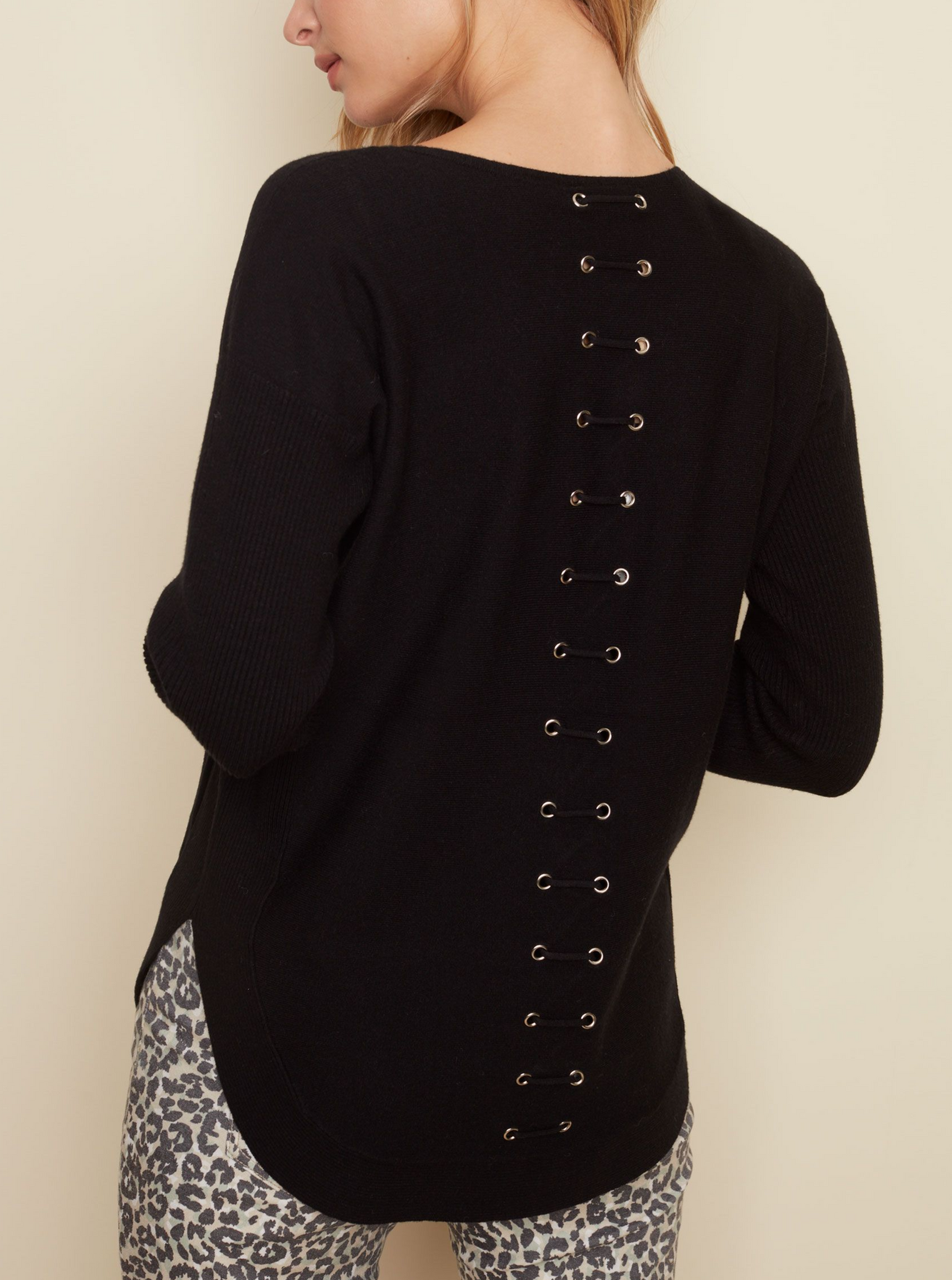 A soft and chic tunic-length sweater with front patch pockets and rounded hem make this sweater stand out, but the real showstopper is the lace-up eyelet detail in the back.  Available in Black and Ginger and Amber.  Long rib sleeves Two front pockets Back lace-up eyelet detail Rounded hem 51% Rayon  27% Polyester 22% Nylon