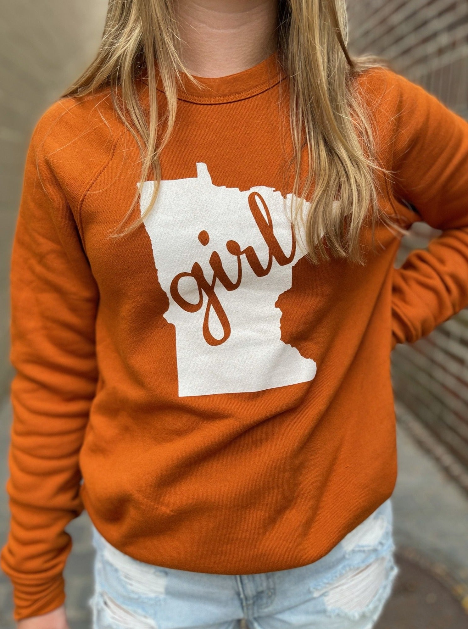 Close up of mn girl state graphic on the autumn burnt orange mn girl crewneck sweatshirt