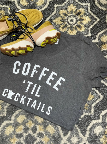 styled flatlay showing connie's tees coffee til cocktails mn womens v neck t shirt with sorel sneakers in dioxide gold